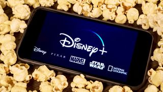 disney plus on a smartphone on a bed of popcorn