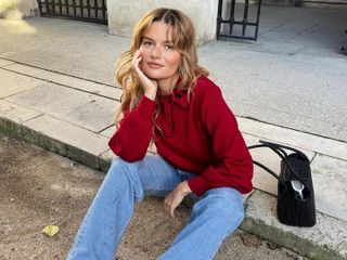 French woman wears a red sweater with red socks, loafers and jeans in Paris