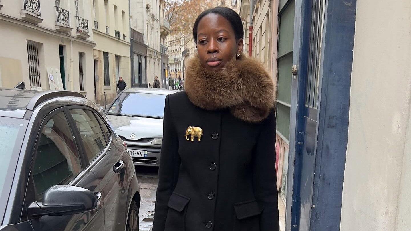 Parisian woman wears a fur stole, black coat and black knee high boots. 