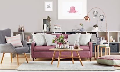 living area with teal wall and pink sofa and wooden floor and shelves and arm chair