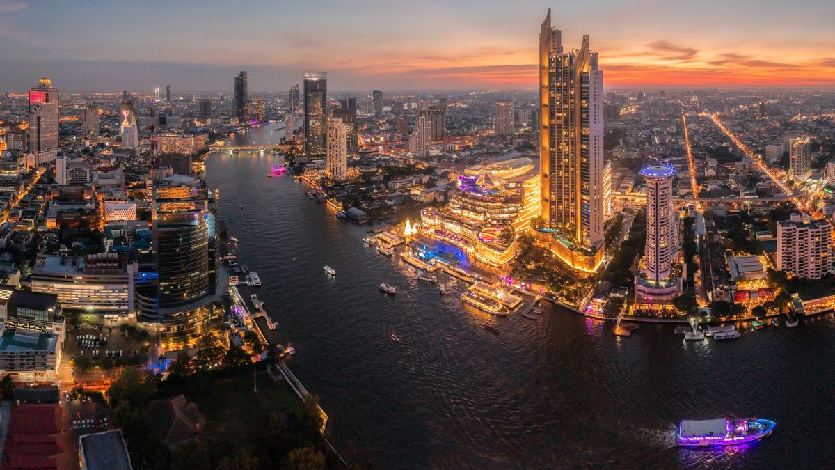 An aerial view of Bangkok city at twilight, showing a river and skyscrapers