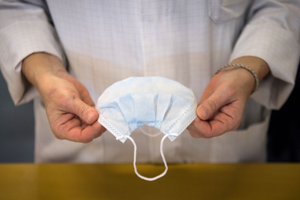 A person holds a disposable face mask.