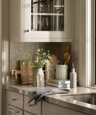 A neutral kitchen with a corner of the countertops decorated with cookbooks and rustic pots