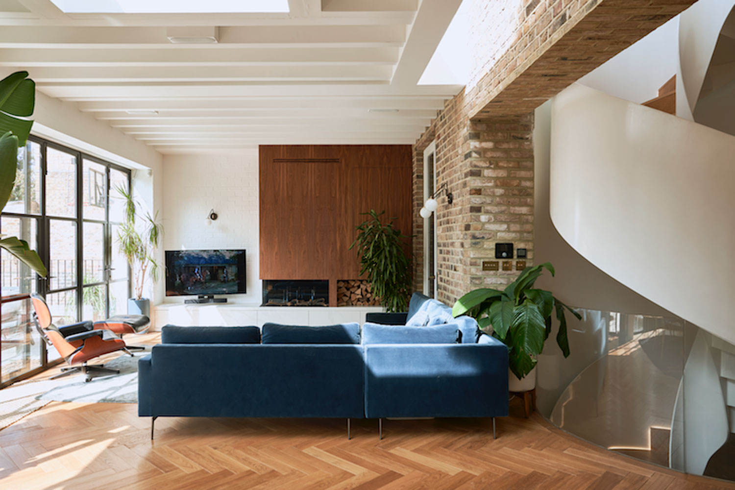a blue sofa in a modern living room with a brick wall and tv in the corner