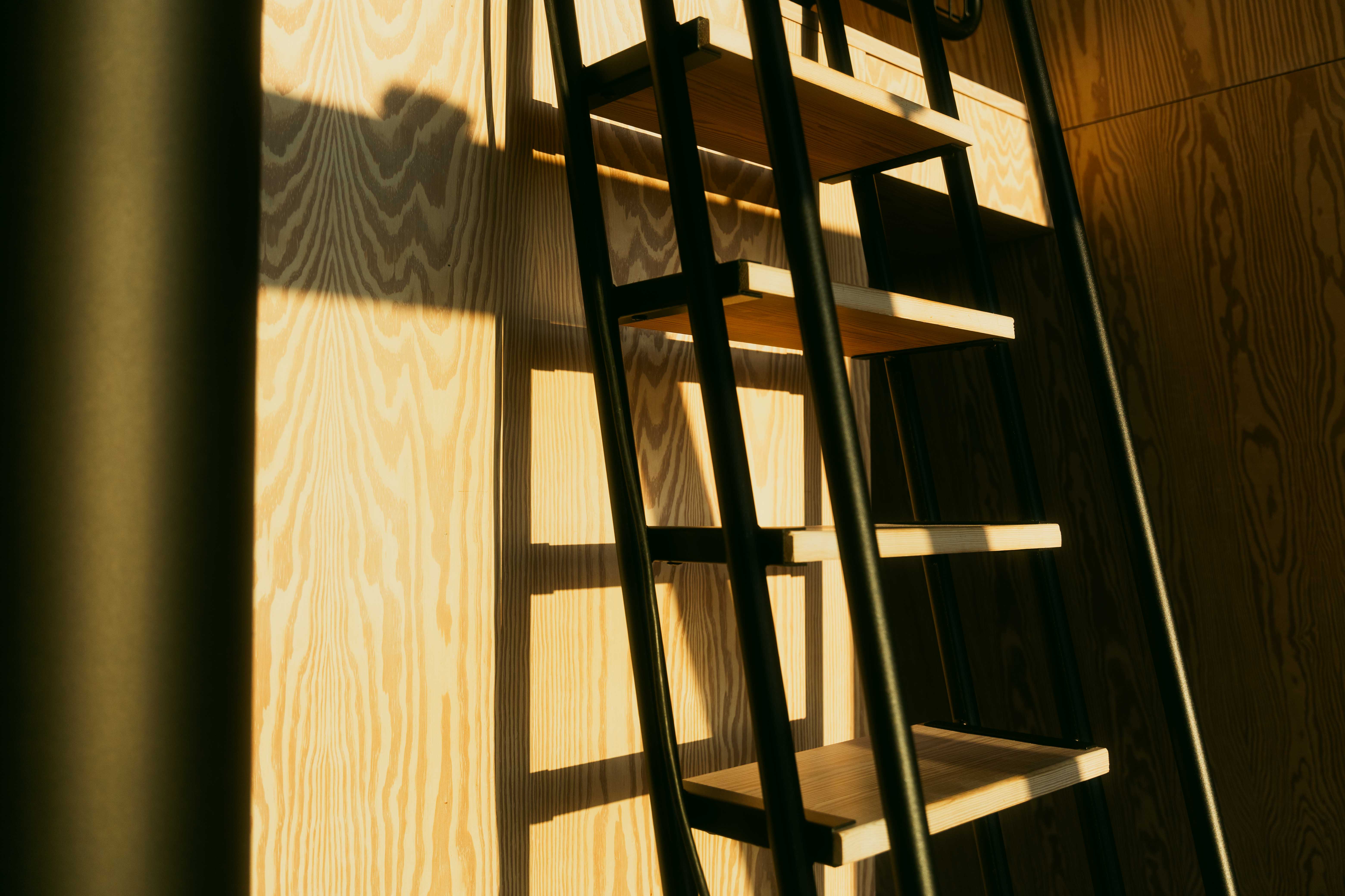 A sun-lit bed ladder in wrought iron and wood.