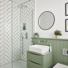 White painted bathroom with green panelling and a green vanity, with a tiled shower space