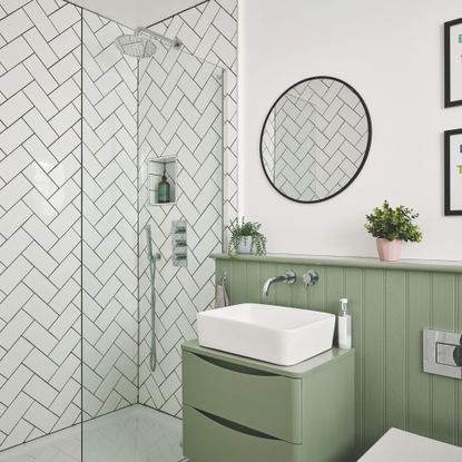 White painted bathroom with green panelling and a green vanity, with a tiled shower space