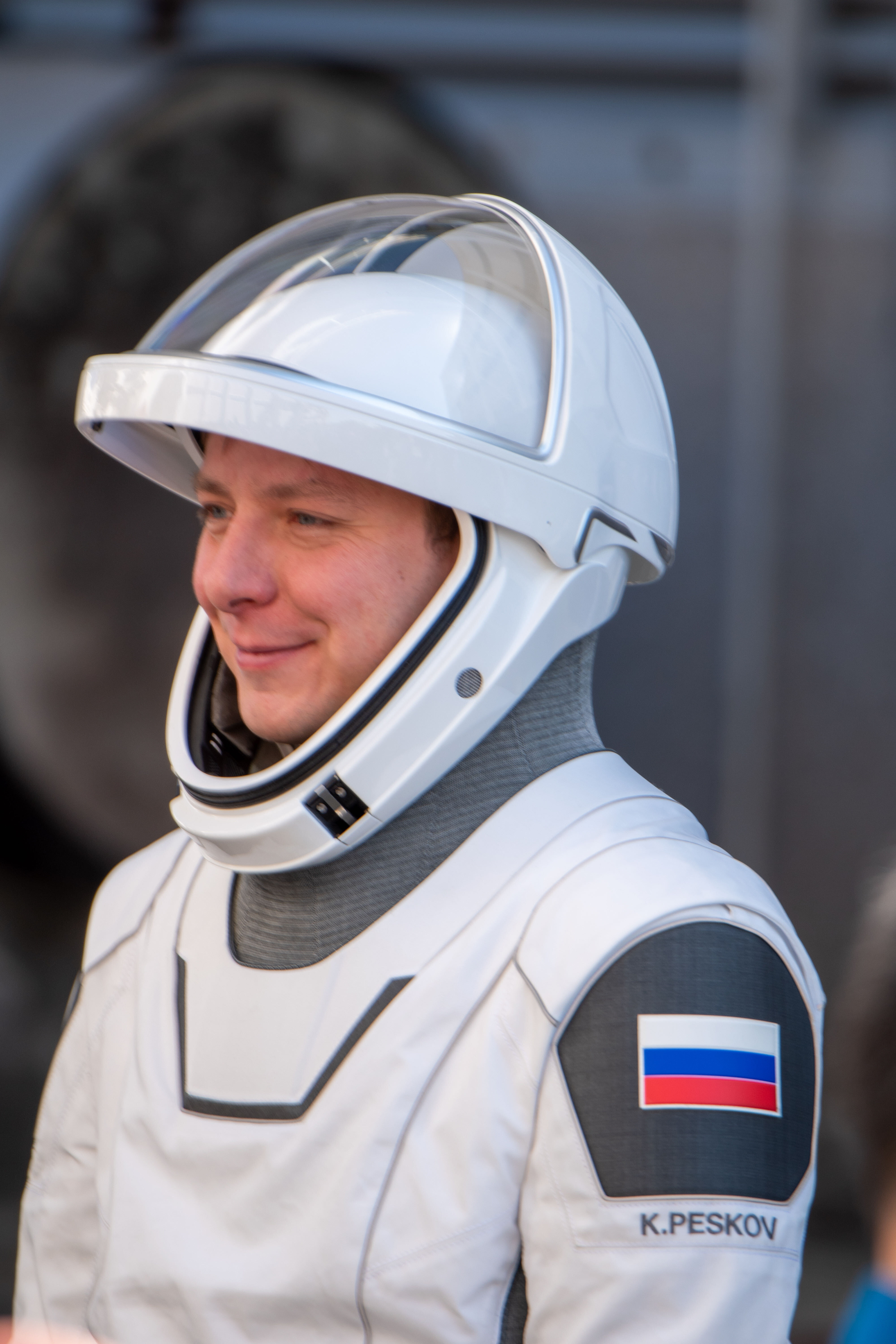 astronauts walk out of a building and board black cars.