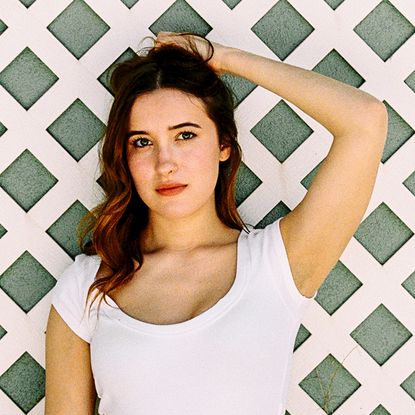 gracie lawrence poses in front of a fence in a white tshirt