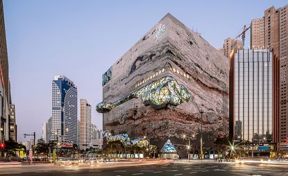 Galleria Gwanggyo department store in South Korea designed by OMA. A large building in a city which was designed in the shape of a rock face. 