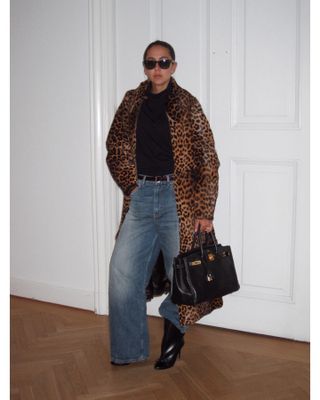 Hanna MW wearing a leopard print pony hair coat with a black top, jeans, boots, and an Hermès bag.