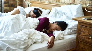 A couple sleep in a bed wearing eye masks