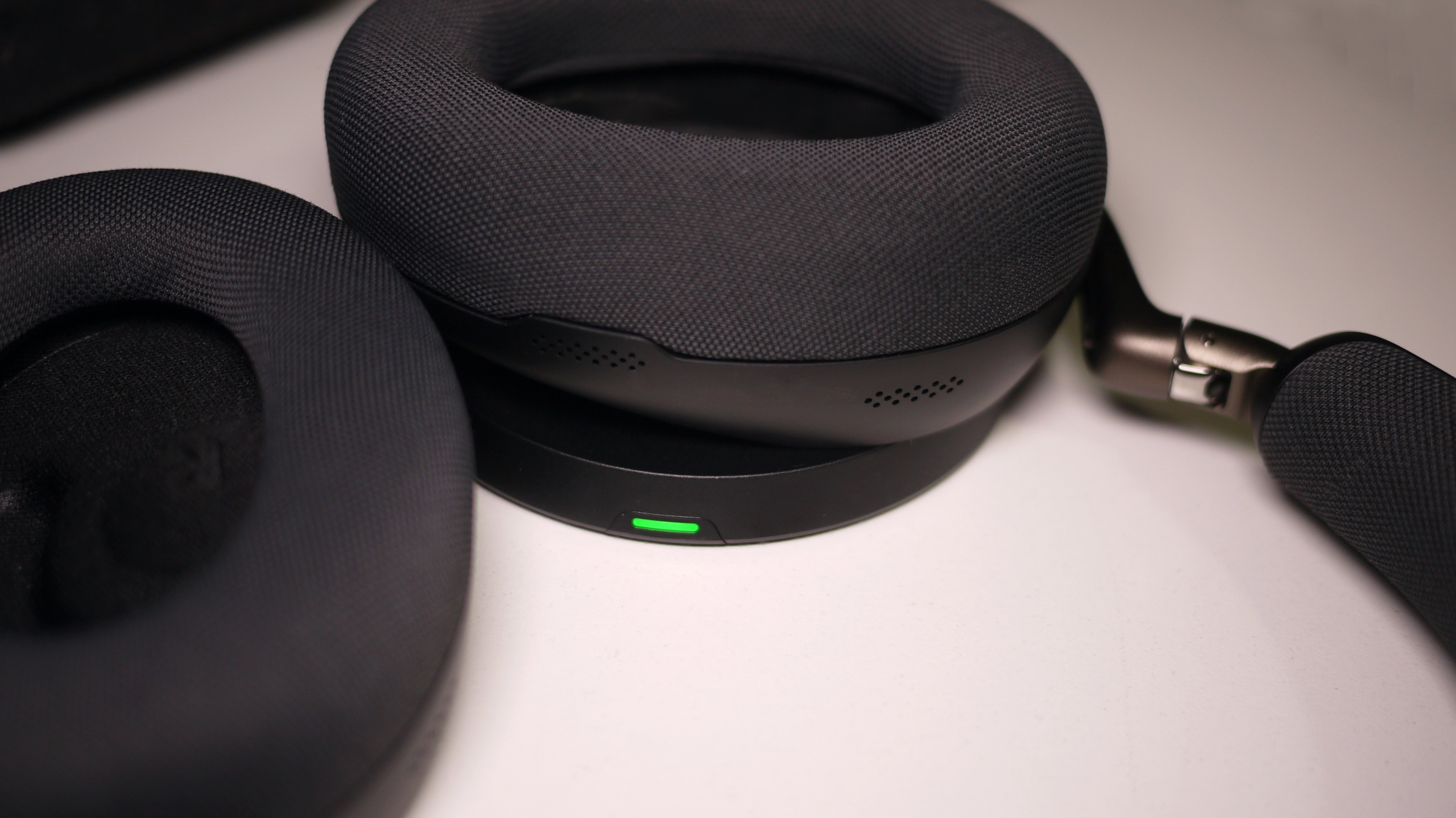 Jabra Evovle3 85 ligger p&amp;aring; den tr&amp;aring;dl&amp;oslash;se oplader p&amp;aring; et bord.