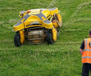 A man operating a remote controlled lawn mower