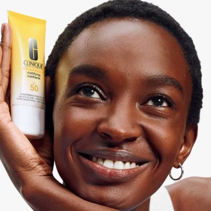 Woman holding Clinique UV Sunscreen