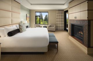 A white bed behind a blue bench in a room at The Allison Inn and Spa in Oregon with mountain views out the window