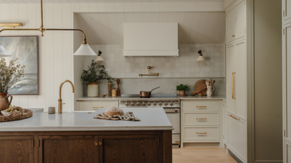 large off-white kitchen with a wooden island and gold hardware throughout