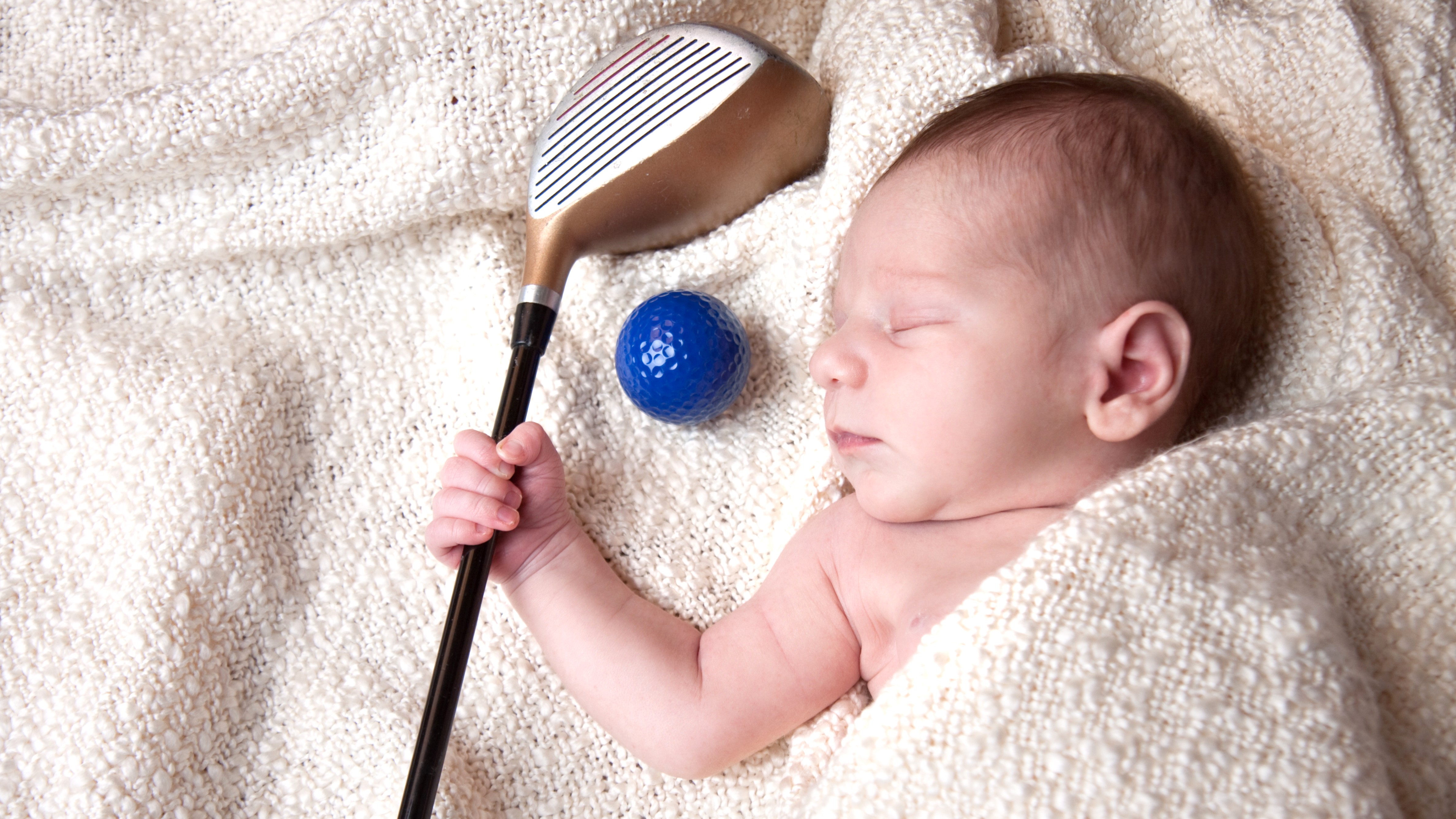 Baby sleeping gripping a golf club