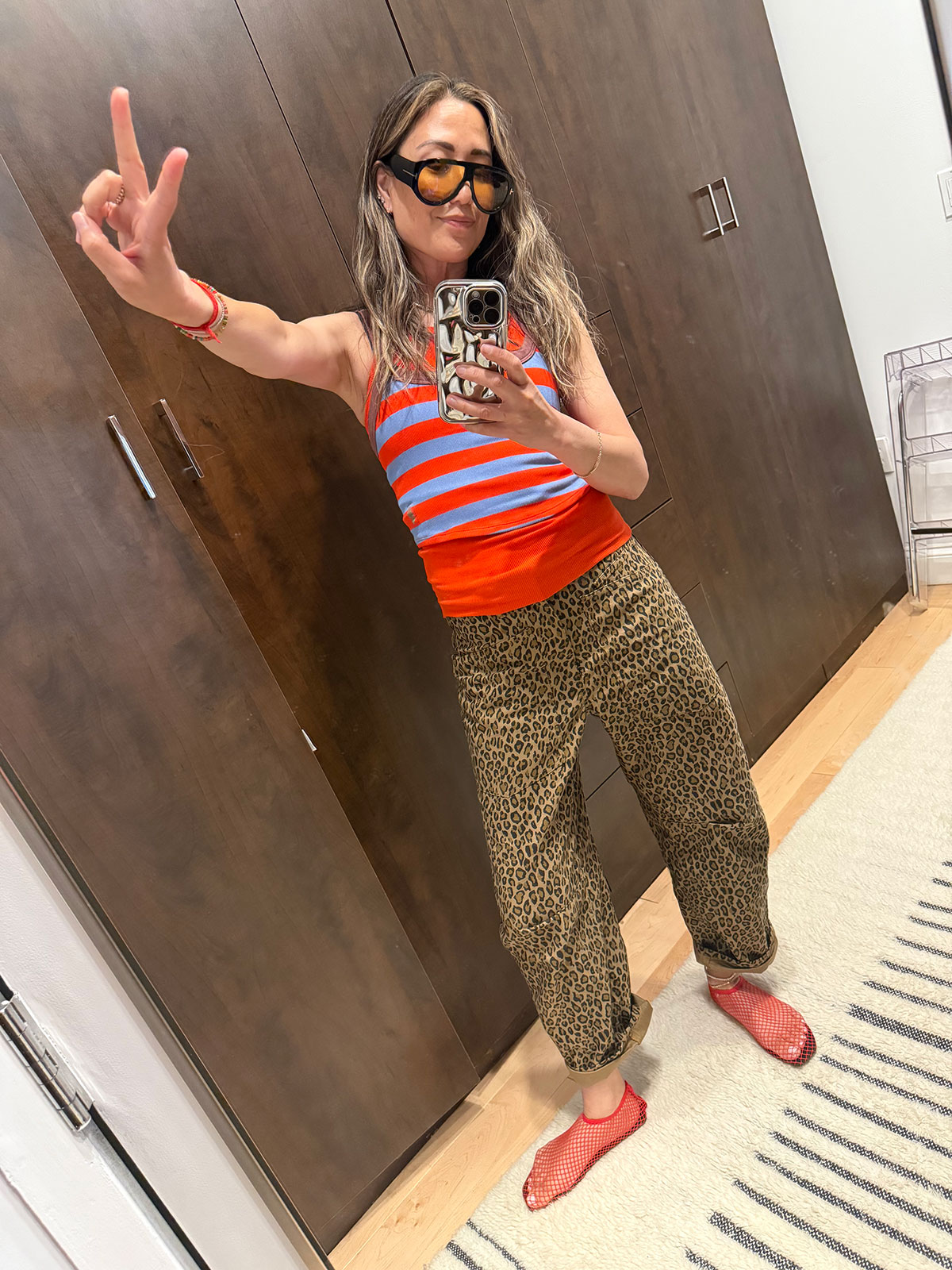 Caroline Maguire wearing leopard pants with a sleeveless striped top and mesh flats.