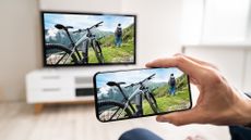 Man mirroring smartphone screen on smart TV