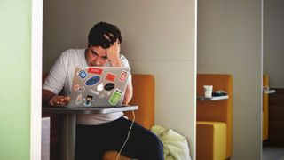 Man at laptop with head in hands