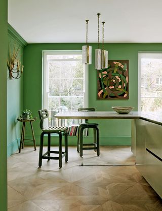 Green kitchen-diner with green painted walls and l-shape table