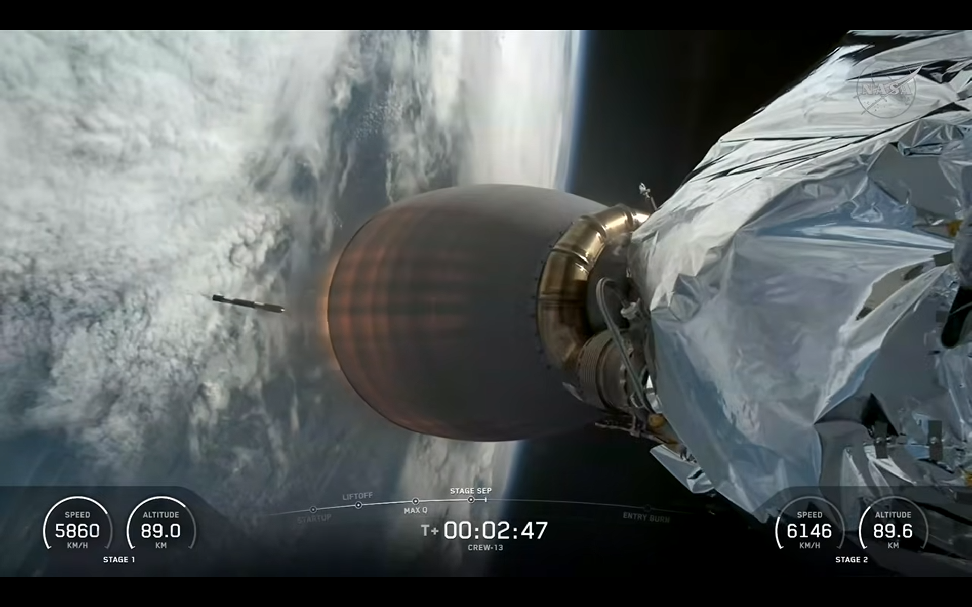 A SpaceX Falcon 9 rocket flies to orbit while its first stage falls away over Earth