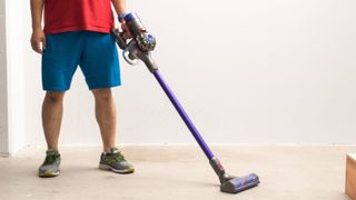A man cleaning a hardwood floor with the Dyson V8 Animal.