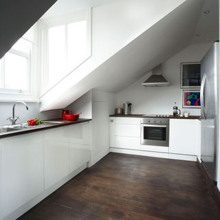 attic kitchen with white cabinet and wooden flooring