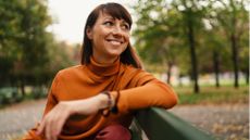 Woman sitting on bench in park smiling