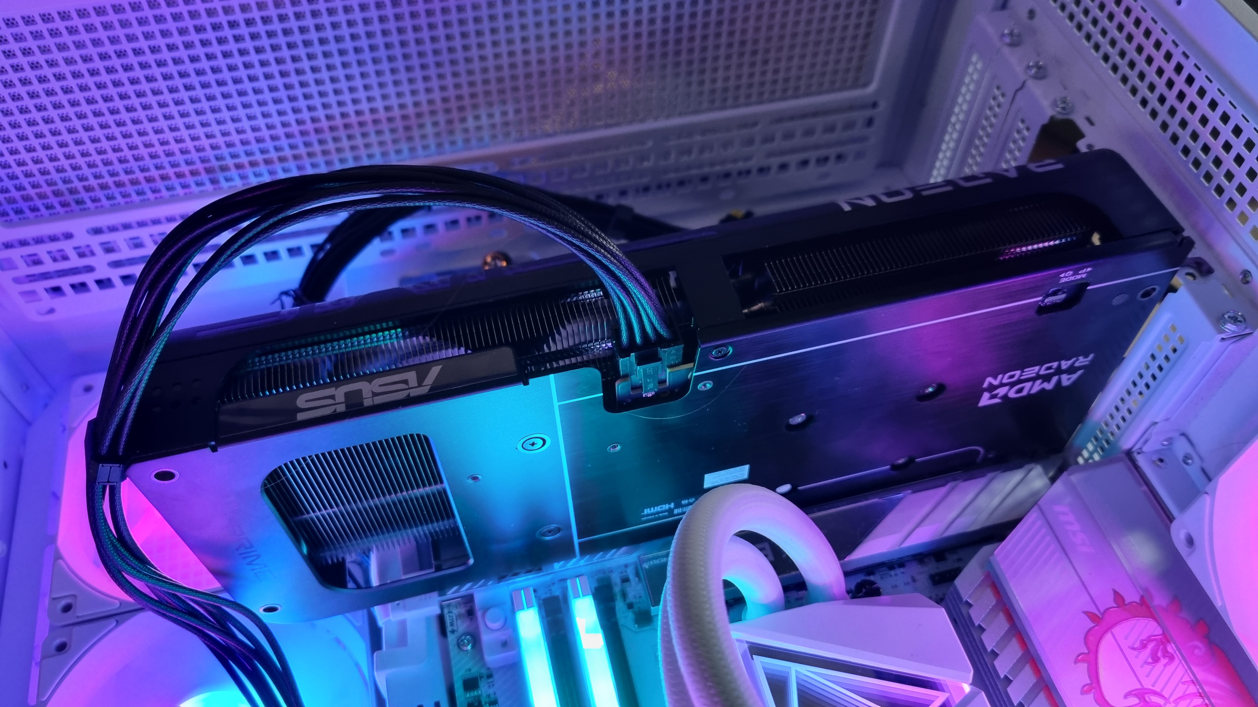 An Asus Prime Radeon RX 9060 XT 8 GB hooked up to a test PC, with power cable in shot