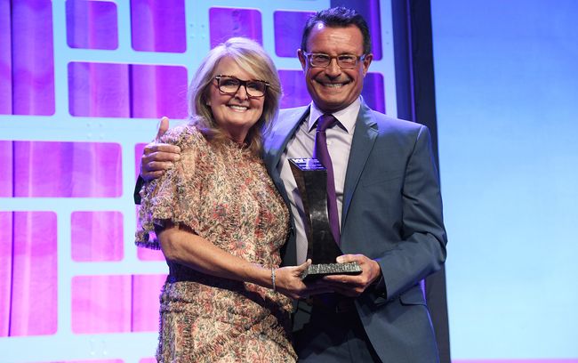 Colleen Langner, executive VP and COO at Cox Communications, accepts the Woman of the Year-Operator award from Cox president Mark Greatrex at the October 10 WICT Touchstones Luncheon.