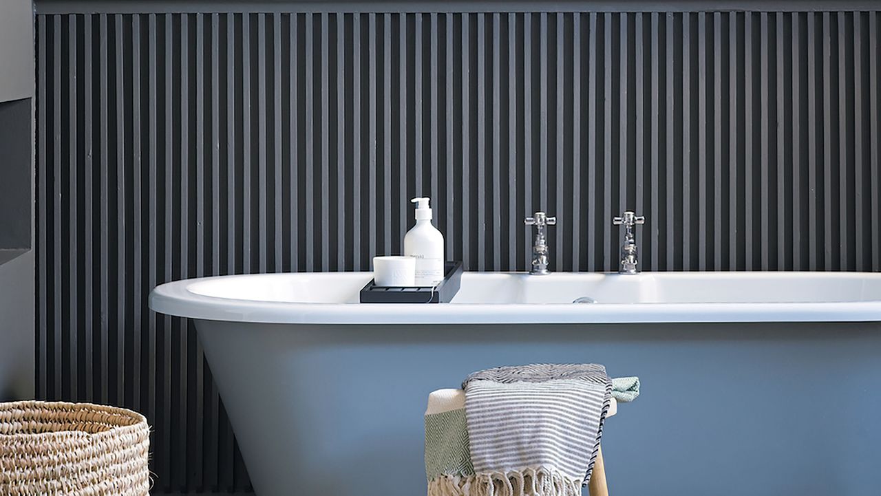 Blue bath in front of grey wall pannelling