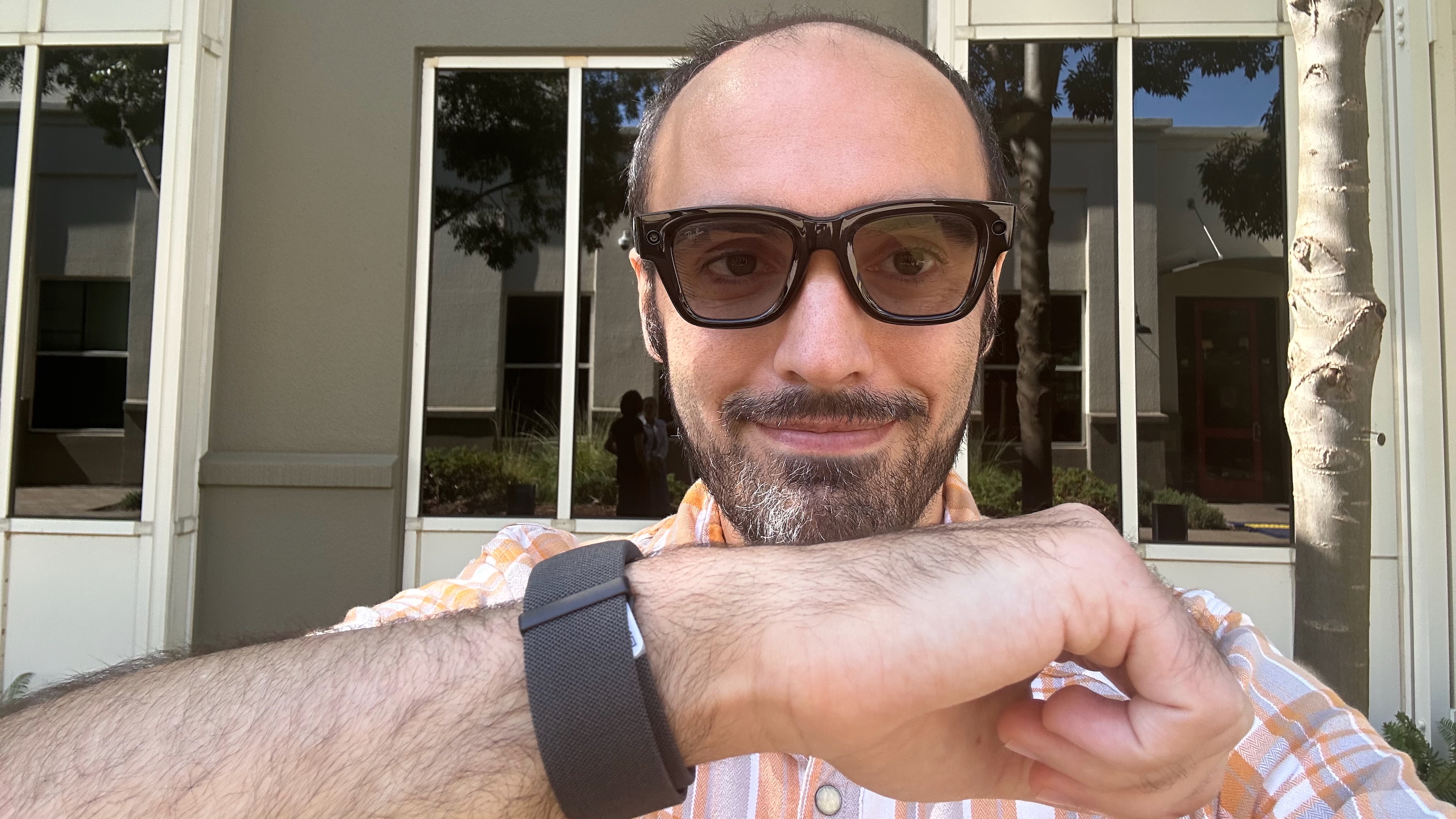 A selfie of the author wearing Meta Ray-Ban Display glasses, holding his wrist with the Meta sEMG band close to the camera.