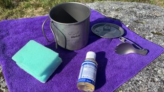 Camping dishes and washing up supplies for camping laid out on a towel