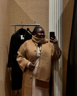  @abimarvel taking a mirror selfie at Toteme in NYC wearing the scarf coat.