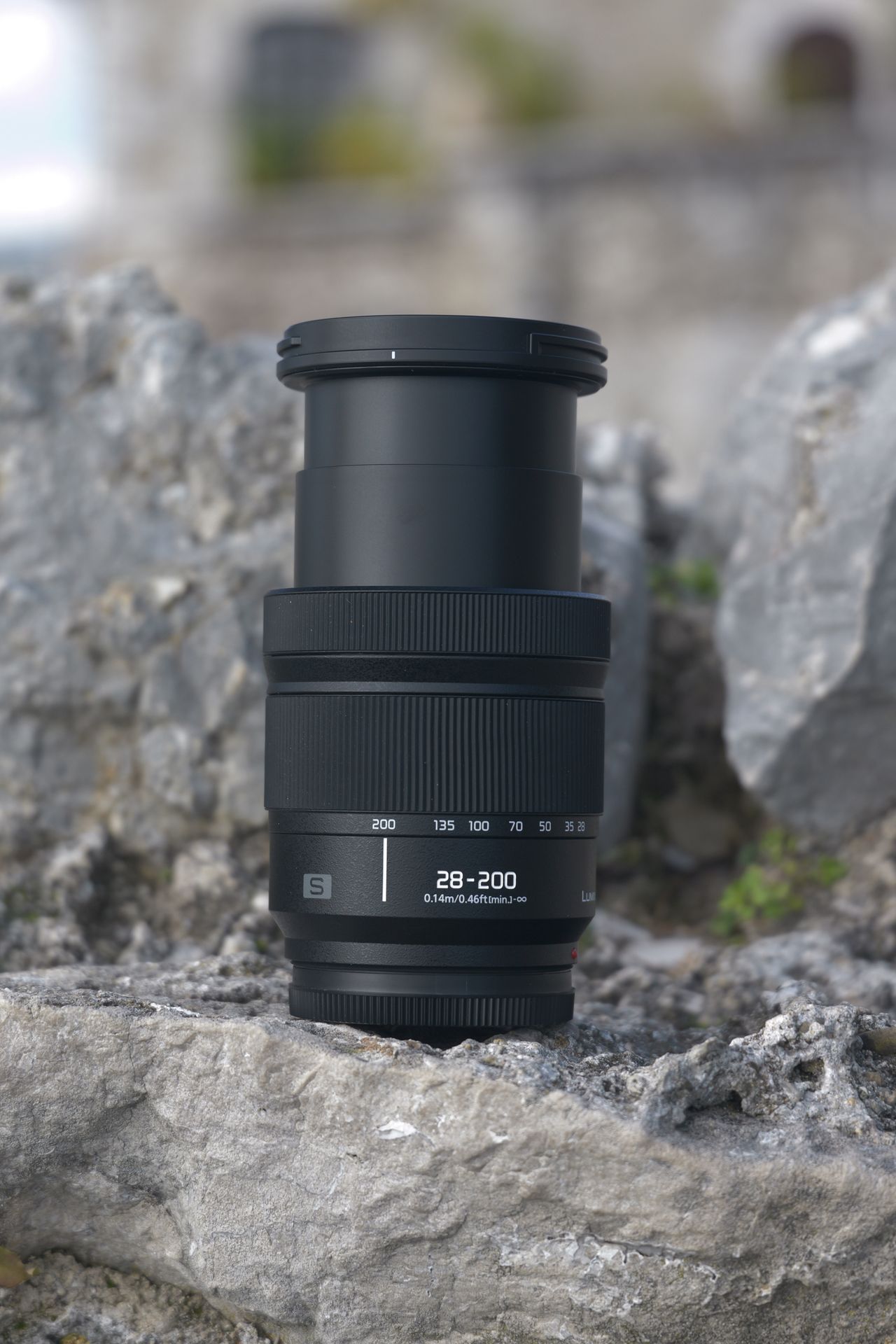 Panasonic Lumix S 28-200mm lens sitting on a rock