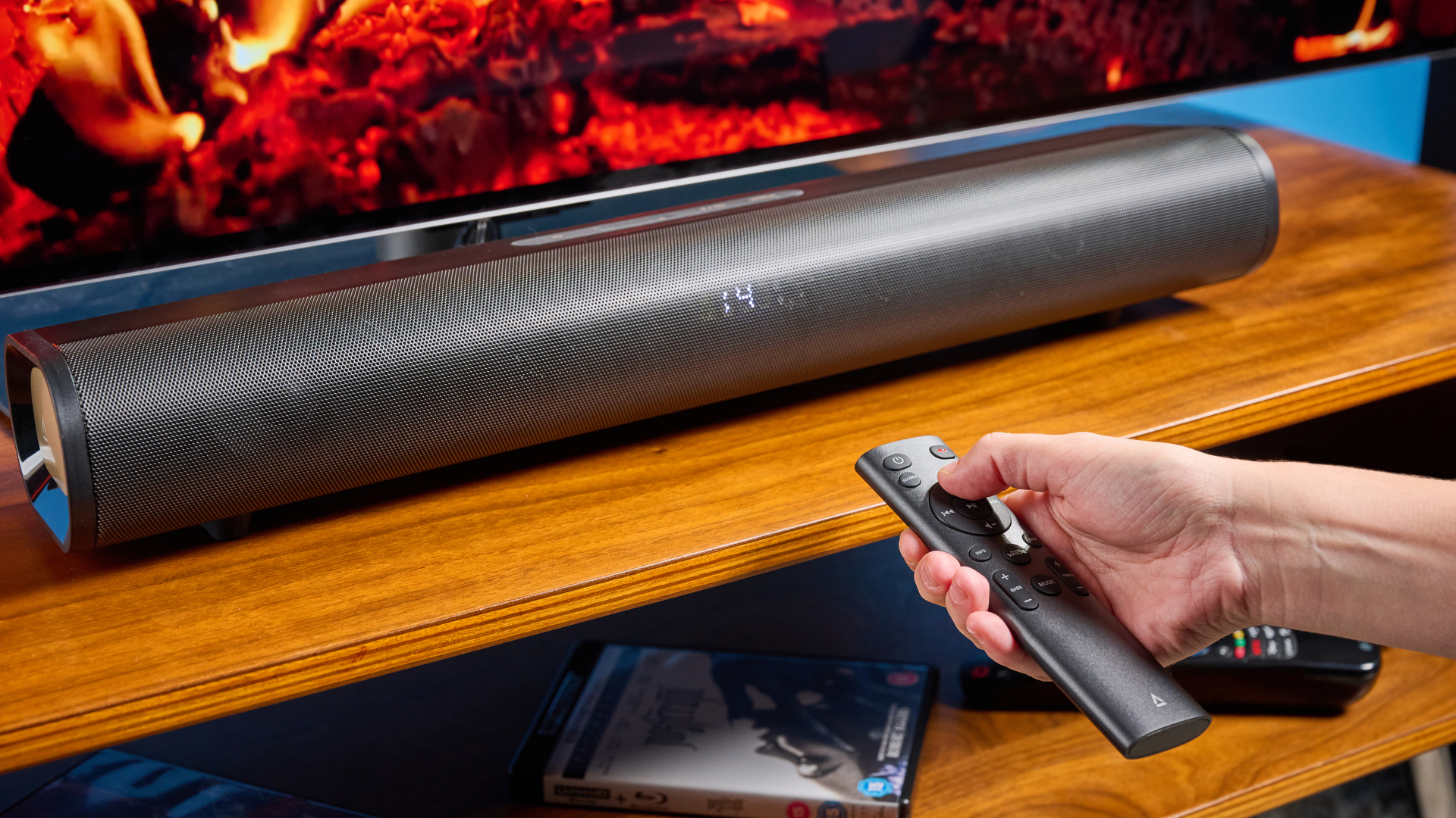 the creative stage pro soundbar and subwoofer, a super-budget home cinema system with 2.1 channels and a remote control photographed on a wooden tv stand with a TV behind