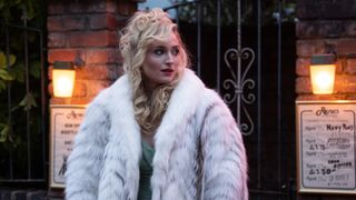 Joan stands outside the nightclub with her fur coat