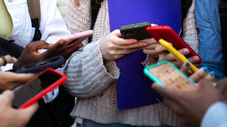 A group of teenagers are seen using their cell phones.