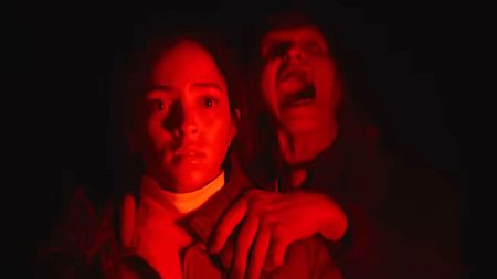 Lou Lloubell as Maddie stands in red light with the Passenger (Joseph Lopez) grabbing her shoulder in the trailer for Passenger.