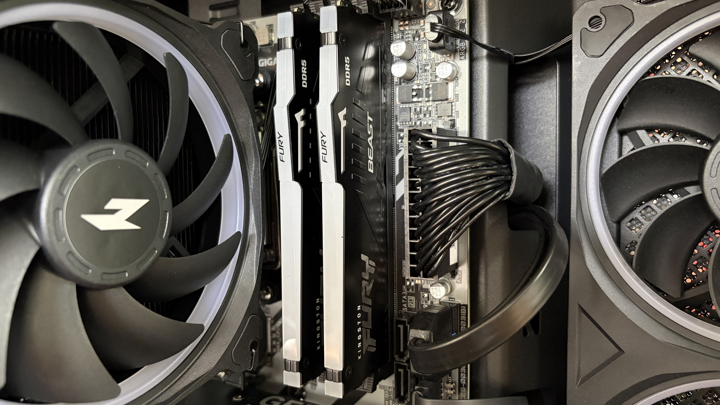 Interior view of a Nitro 65 computer case featuring two RAM sticks labeled "FURY" and "BEAST," a cooling fan, and wiring against a dark motherboard.