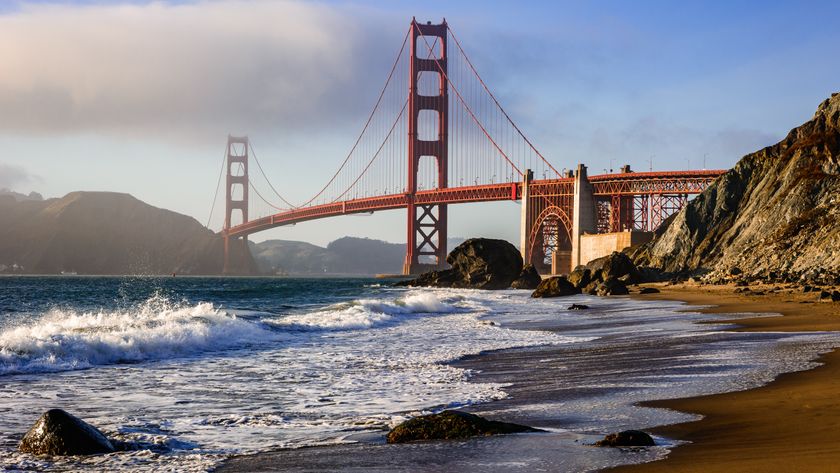 A photograph of waves lapping at the shoreline of Marshall&#039;s Beach in San Francisco with the Golden Gate Bridge in the background. 