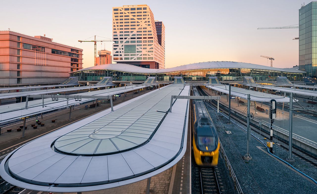 An exterior view of the train station showing the tracks and passenger platforms with a yellow and black train going through