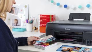 woman looking at a photo printer coming out of a Canon Pixma 620 printer