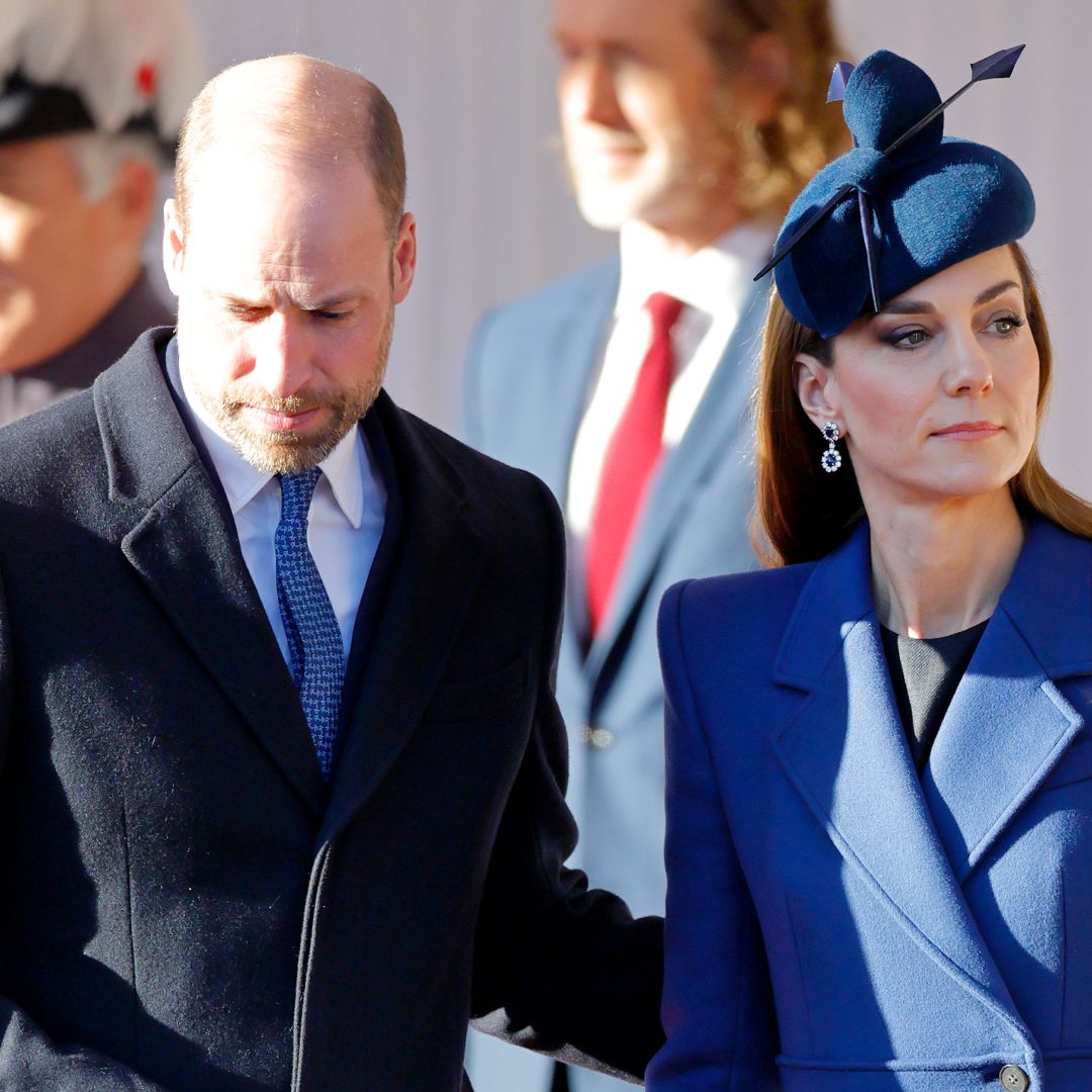 Prince William wearing a dark coat putting his arm around Kate, in a blue coat and hat