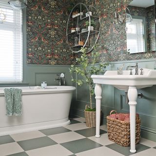 white sink and freestanding bath on top of checkered tiles and next to green panelling and wallpaper