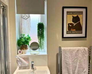 Febreze Small Space air freshener in neutral small bathroom with cat art on the wall and hanging macramé and plants