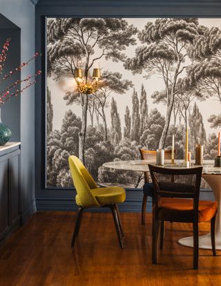 A blue dining room with a black and white wallpaper feature wall and gold accents