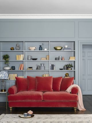 blue living room with painted alcove shelving, coral velvet sofa